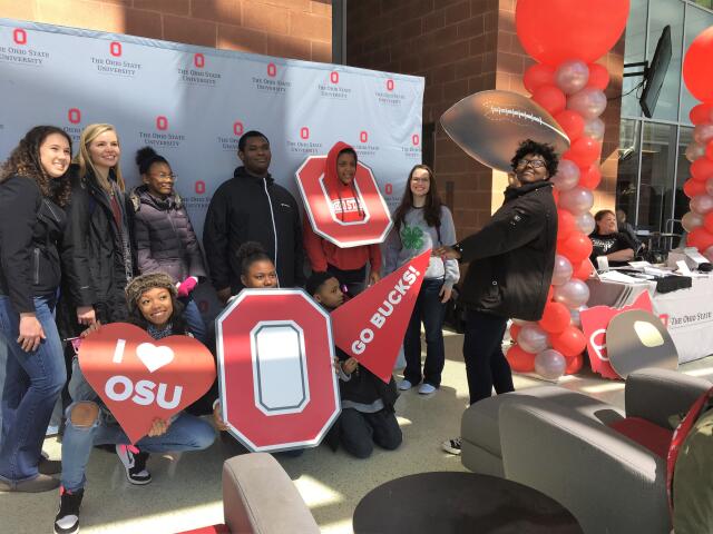 Students pose in front of an Ohio State backdrop.